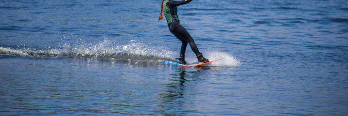 The man does wakeboarding on the water in the summer in a helmet and wetsuit.