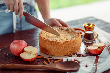 Woman cutting homemade apple pie on rustic dark background. Classic autumn Thanksgiving dessert - organic apple pie.