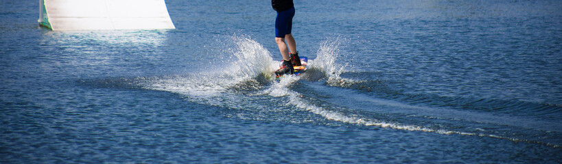 The man does wakeboarding on the water in the summer in a helmet and wetsuit.