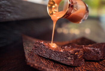 Caramel brownie dessert bars on rustic dark background