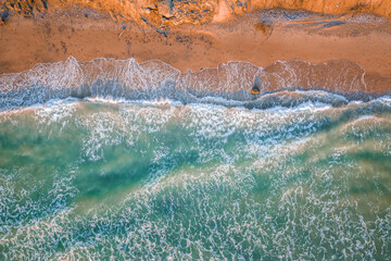 Baltic sea in stormy weather with turquiose water and impressive waves. Sandy coastline in sunlight.