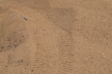 Yellow sand with some rock particles and visible tyre mark. Such mixture is often used in road construction. 