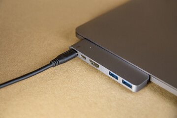 type-s wire connected to a macbook on an ocher background