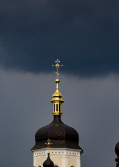 church dome with a cross with rain clouds on the background