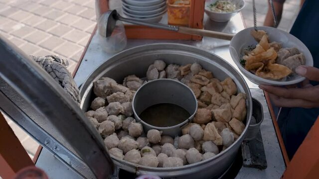 bakso. indonesian famous meatball street food vendor close up hand serving