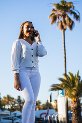 Fototapeta na wymiar Happy African American woman in white clothes talking with her phone