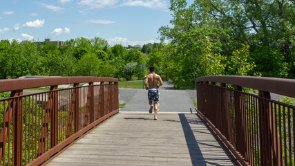 Cornwall, Ontario, Canada - 2020 June 6th man jogging without a shirt in Lamoureux Park