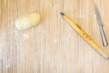 A piece of dough, old wooden rolling pin and a knife on wooden background