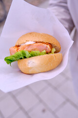 woman holds burger with salmon and salad