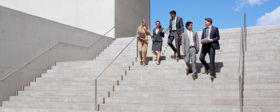 Business people talking and descending urban stairs