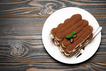 Classic tiramisu dessert on ceramic plate on wooden background