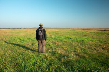 A lone man with a backpack standing in front of a huge empty space