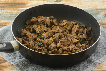 Cooking sliced beef, spinach and mushrooms for Mexican food filling in frying pan