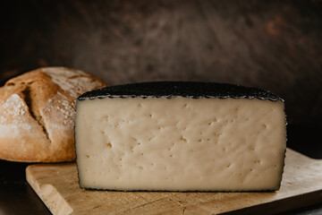 portion of half cured manchego cheese, with rustic village bread, and artisan breadsticks