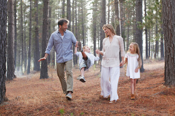 Naklejka na ściany i meble Happy family holding hands and walking in woods