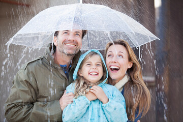 Enthusiastic family under umbrella in downpour