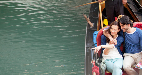 Smiling couple riding in gondola on canal in Venice