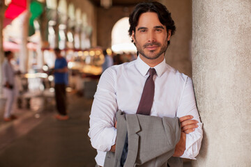 Portrait of smiling businessman leaning on pillar with arms crossed