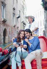 Smiling couple taking self-portrait digital camera in gondola on canal in Venice © Sam Edwards/KOTO