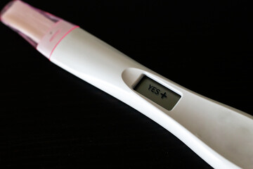 Close up image of digital positive pregnancy test with uniform background