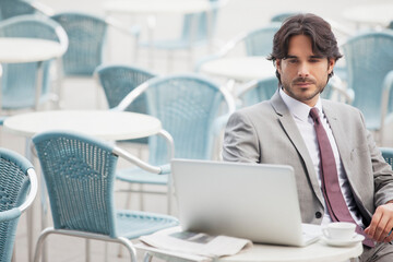 Businessman using laptop at sidewalk cafe