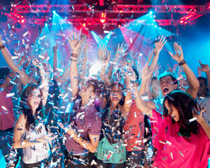Confetti falling over enthusiastic crowd on dance floor of nightclub