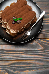 Classic tiramisu dessert on ceramic plate on wooden background