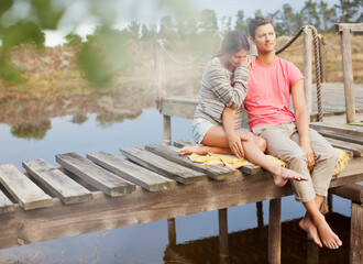 Serene couple siting on dock over lake