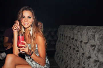 Portrait of smiling woman drinking cocktail in nightclub