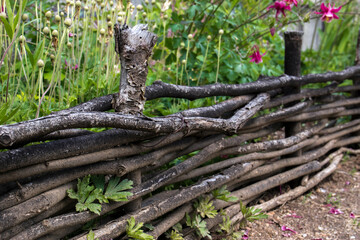 Wicker rustic wooden fence made of sticks in close-up. Texture, background. Road to the fence. Perspective.