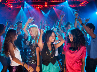 Smiling friends dancing on dance floor of nightclub