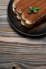 Classic tiramisu dessert on ceramic plate on wooden background