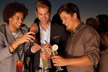 Smiling men toasting cocktails in nightclub