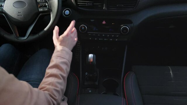 A woman's hand is shifting an automatic gear shift knob in modern car. Rear view.