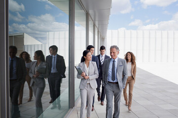 Smiling business people walking along building
