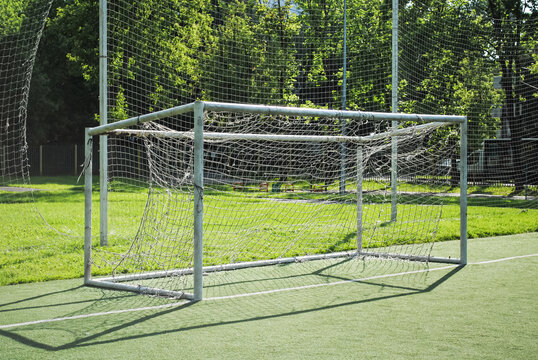 Soccer goal on a school soccer field on a sunny summer day. Amateur football, goal with a torn and dirty net. Selective focus image.
