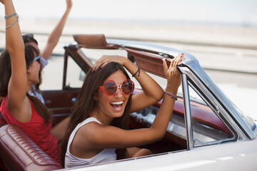 Smiling women driving convertible