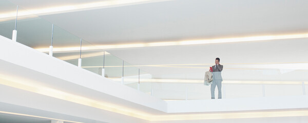 Businessman at glass balcony railing in modern office