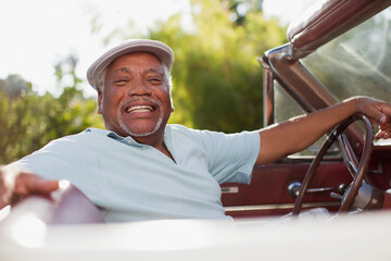 Smiling older man driving convertible
