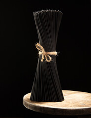 Black raw spaghetti on wooden table on black background.Black Italian pasta.Close up.