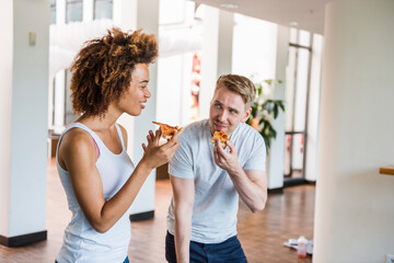 Young business people sharing pizza for lunch in a modern office with ping pong table