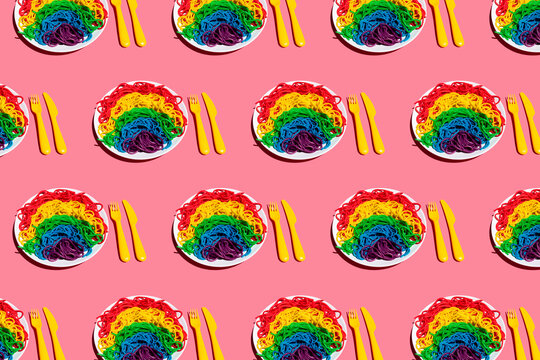 Pattern of plates with?rainbow-colored?spaghetti against pink background