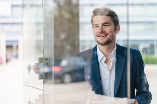 Smiling young businessman using tablet in the city