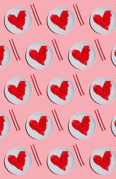 Pattern of plates with red-colored heart-shaped spaghetti against pink background