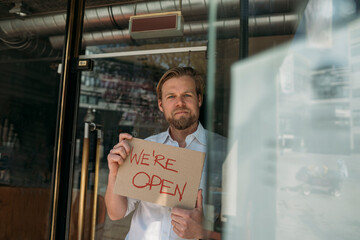 Shopkeeper holding cardboard with opening announcement in the city