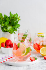 Cold summer drink - strawberry lemonade with mint and ice cubes in glass. Vertical, copy space.