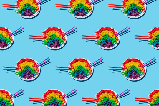Pattern of plates with?rainbow-colored?spaghetti against blue background