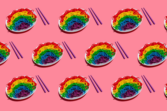 Pattern of plates with rainbow-colored spaghetti against pink background