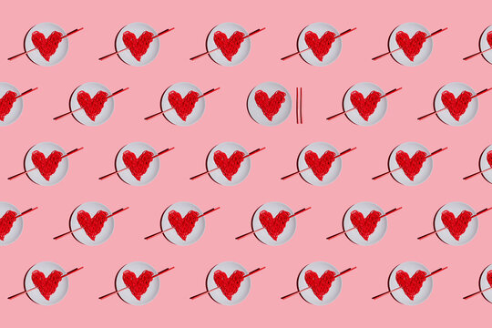 Pattern of plates with red-colored heart-shaped spaghetti against pink background