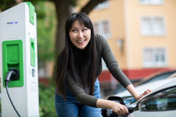 Carsharing, woman charging an electric car